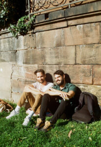 Two college men sitting by a wall